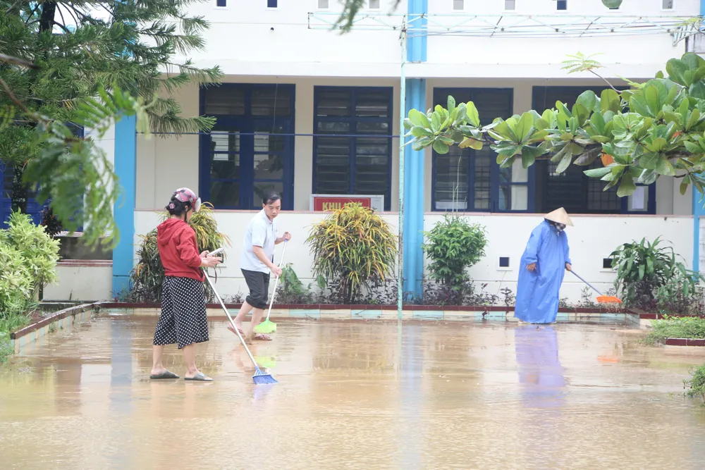 Cô Vân cùng các giáo viên trong trường đang dọn bùn. Ảnh: NGÔ QUANG