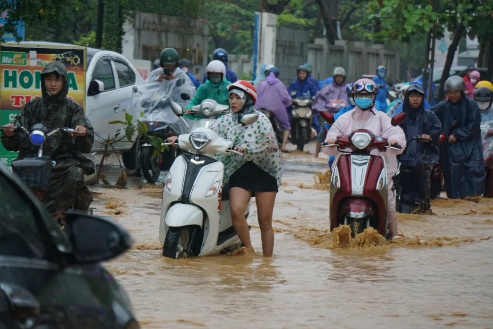 Người dân gặp khó khăn khi lưu thông qua các đoạn bị ngập. Ảnh: NGÔ QUANG