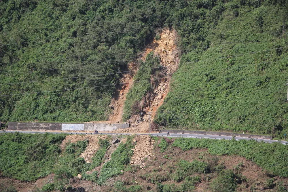 Một khối lượng đất đá lớn đổ từ trên núi cao xuống đường lên đỉnh đèo Hải Vân khiến xe cộ di chuyển khó khăn. Ảnh: NGÔ QUANG