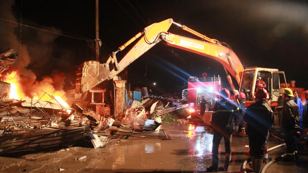 Dùng xe múc phá tường để tiếp cận đám cháy.Ảnh: NGÔ QUANG