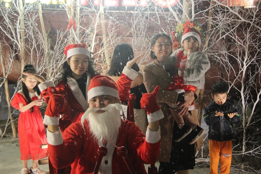 Các em nhỏ chụp hình với ông già Noel trong làn tuyết nhân tạo.