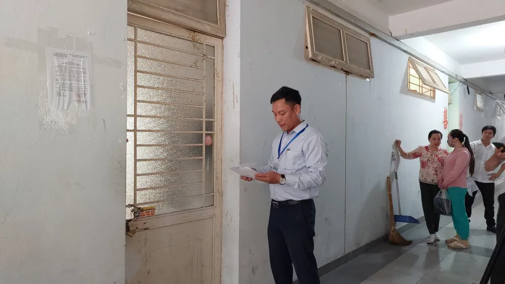 Lực lượng chức năng đọc quyết định thu hồi một chung cư thuộc sở hữu Nhà nước tại quận Sơn Trà.Ảnh: GH