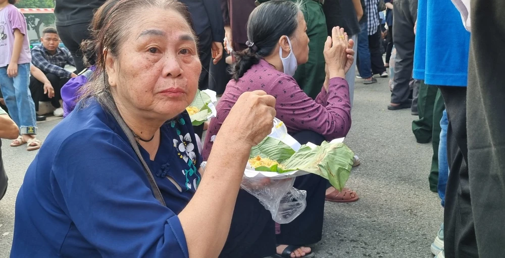 Bà Vũ Thị Hoa ăn vội miếng xôi chờ đến lượt vào viếng Tổng Bí thư Nguyễn Phú Trọng. Ảnh: V.LONG tong-bi-thu-nguyen-phu-trong-ve-voi-dat.jpg.jpg