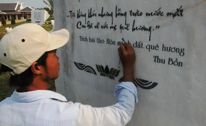 Công nhân tiến hành sửa chữa lỗi chính tả trên tảng đá khắc bài hát “Người mẹ Quảng Nam”chiều 14-3 - Ảnh: TRƯỜNG TRUNG