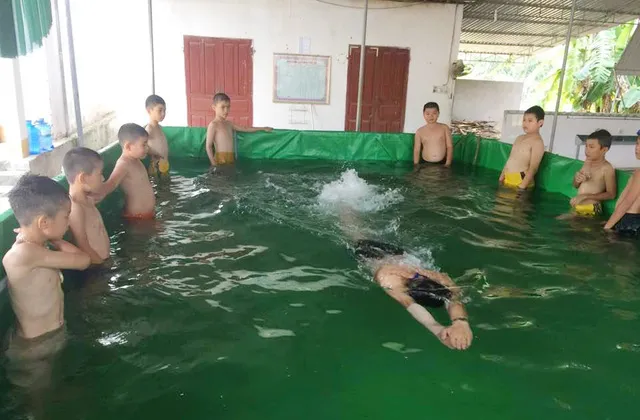 Các học sinh Trường Tiểu học thị trấn Anh Sơn học bơi trong chiếc bể mini của thầy Thanh dưới sự hướng dẫn của giáo viên thể dục.