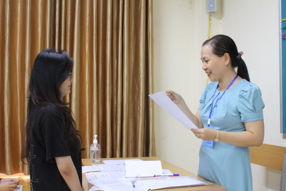 Cán bộ coi thi xác nhận thông tin trên giấy báo dự thi cho thí sinh. Ảnh: Minh Trúc