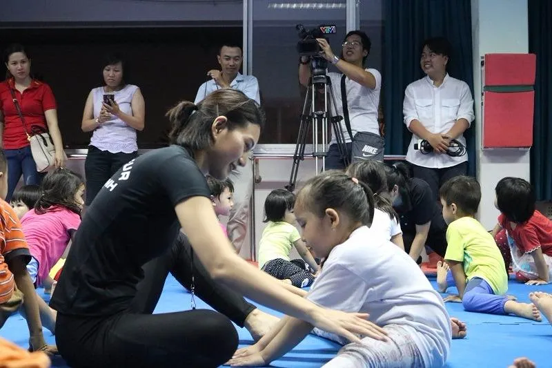 Cô giáo hướng dẫn động tác cho một bé gái.