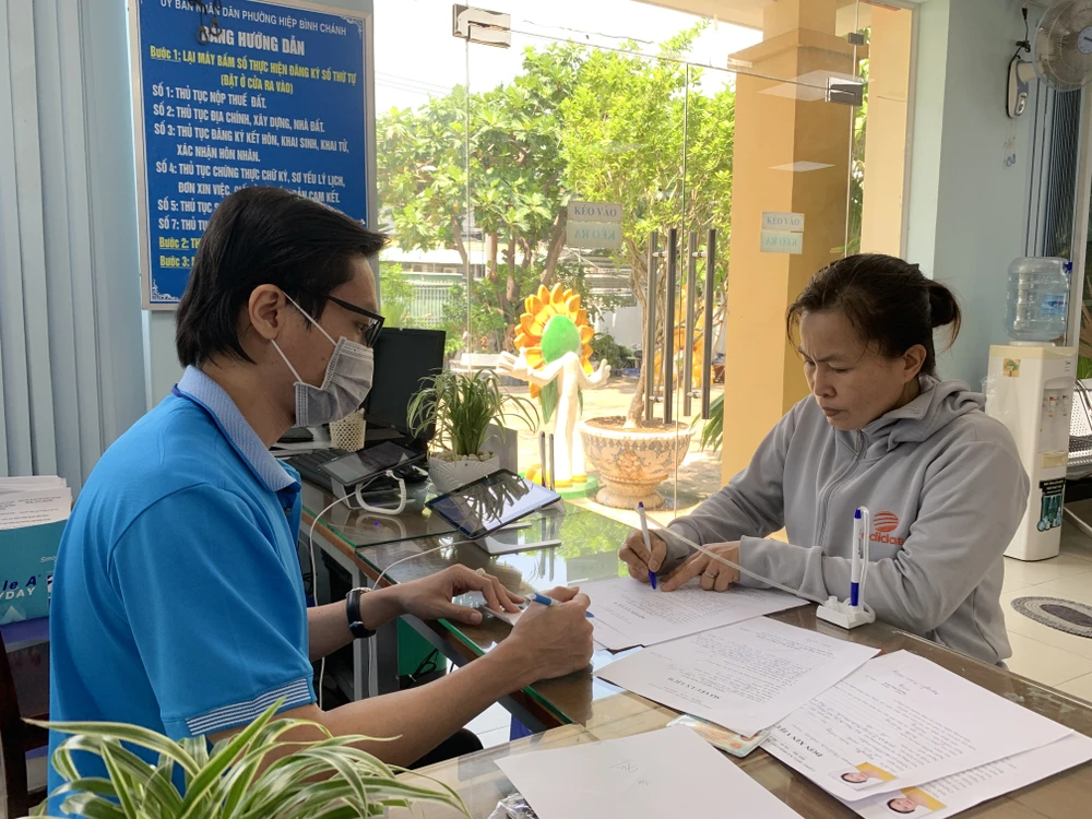 Thanh niên phường hướng dẫn người dân điền các thông tin về sơ yếu lý lịch. Ảnh: THANH TUYỀN Cán bộ phường đông dân nhất Thủ Đức 'tăng ca' giải quyết thủ tục trong ngày cho dân-ngay-hoi-giai-quyet-thu-tuc-phuong-dong-dan-thu-duc-hiep-binh-chanh12.JPG