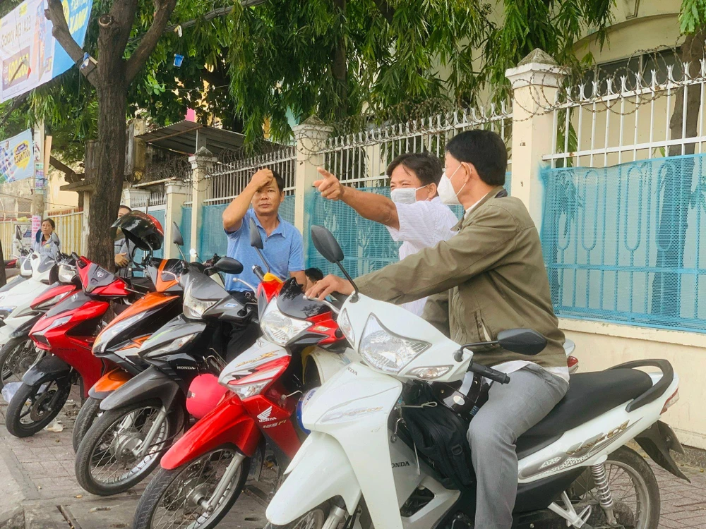 Ông Đắt (chính giữa) ngồi trò chuyện với các phụ huynh khác trong lúc chờ con thi. Ảnh: THẢO PHƯƠNG