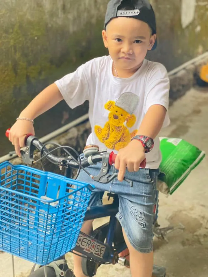 Bé Bo chở gạo trên chiếc xe đạp và tự tay trao cho các cụ già. Ảnh: NVCC