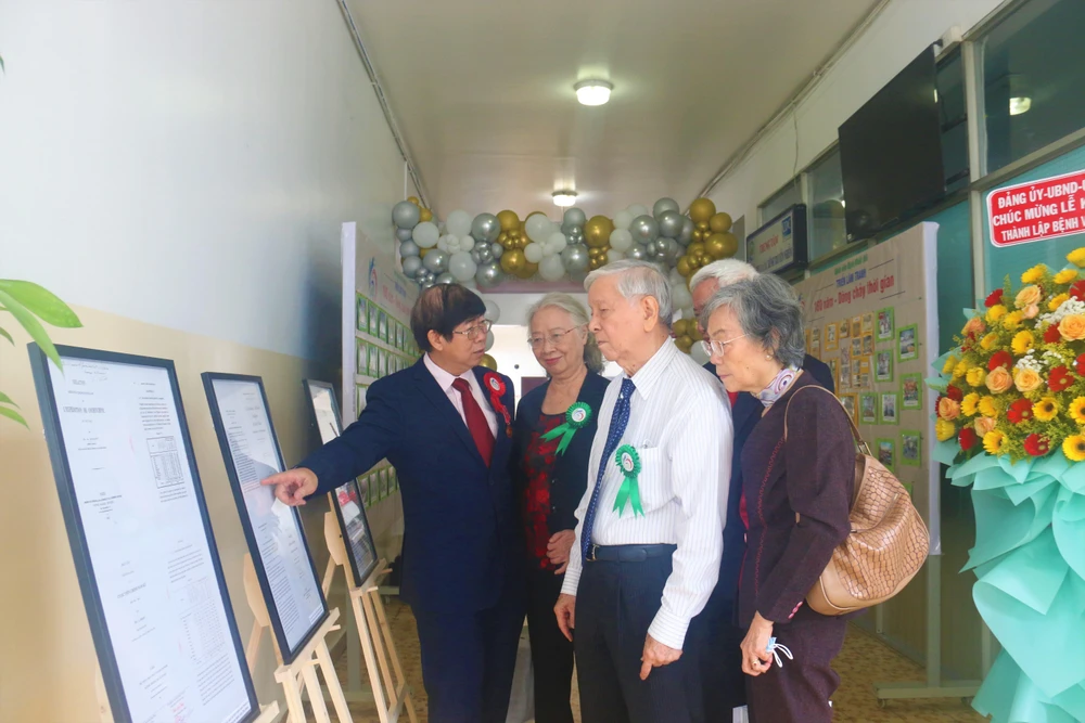 TS-BS Lê Mạnh Hùng, Phó Giám đốc bệnh viện hướng dẫn khách mời tham quan triển lãm ảnh BV. Ảnh: THẢO PHƯƠNG