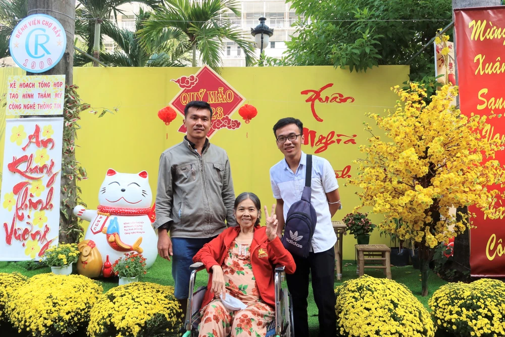 Bệnh nhân cùng thân nhân chụp ảnh kỉ niệm tại đường hoa xuân. Ảnh: TRẦN MINH