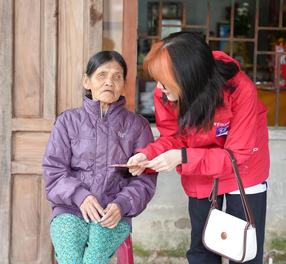 Nguyễn Minh Chiêu tặng lì xì cho cụ bà. Ảnh: BTC