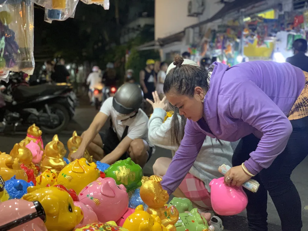 Vừa giới thiệu những chú heo cho khách hàng, chị Nga (chủ sạp heo đất) cho biết chị mở sạp bán heo đất tại quận Bình Tân đã được 10 năm. Chị kể ngày thường chỉ bán được vài ba con, chủ yếu chị bán tạp hóa, đồ chơi trẻ em. Riêng dịp Tết, đặc biệt là mùng 10 tháng giêng, chị bán heo đất rất đắt khách. Ảnh: THẢO PHƯƠNG