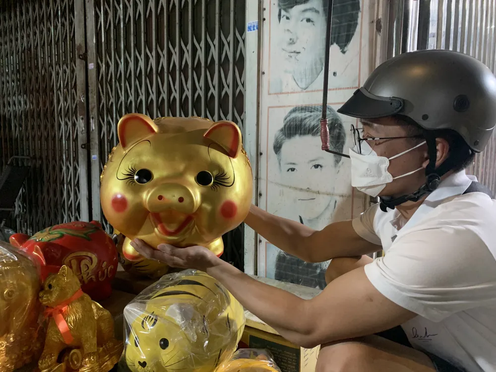 Anh Nguyễn Thành Tín (ngụ Bình Tân) cầm trên tay chú heo vàng bằng sứ có giá 900 nghìn đồng. Ảnh: THẢO PHƯƠNG