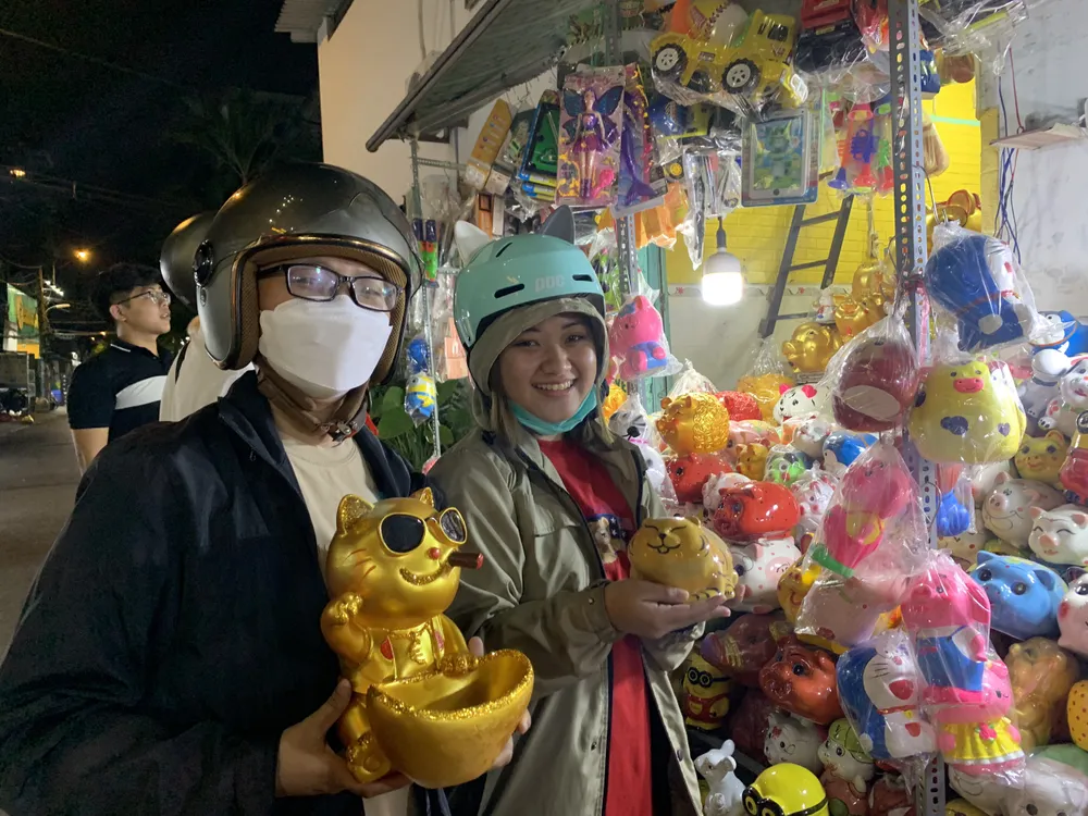 Sau một hồi chọn lựa thật kĩ, chị Nguyễn Ánh Ngọc (27 tuổi, ngụ quận 11) đã quyết định mua chú mèo thần tài để gửi gắm may mắn tiết kiệm. Chú mèo đeo kính hút thuốc này được người bán giới thiệu “giữ tiền là không ai lấy được của mình”. Được biết đây là lần đầu chị mua heo đất vào ngày vía Thần Tài. Ảnh: THẢO PHƯƠNG