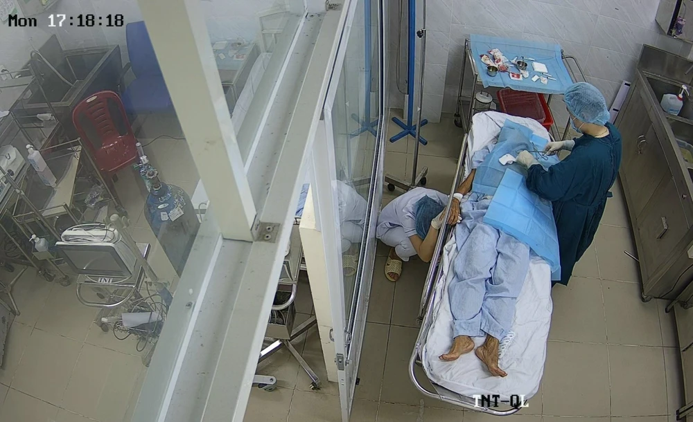 Hình ảnh chị Châu Thị Yến Trinh ngồi sụp cạnh băng ca, nắm chặt tay bệnh nhân là một cụ bà 77 tuổi đang được phẫu thuật. Ảnh: BVCC