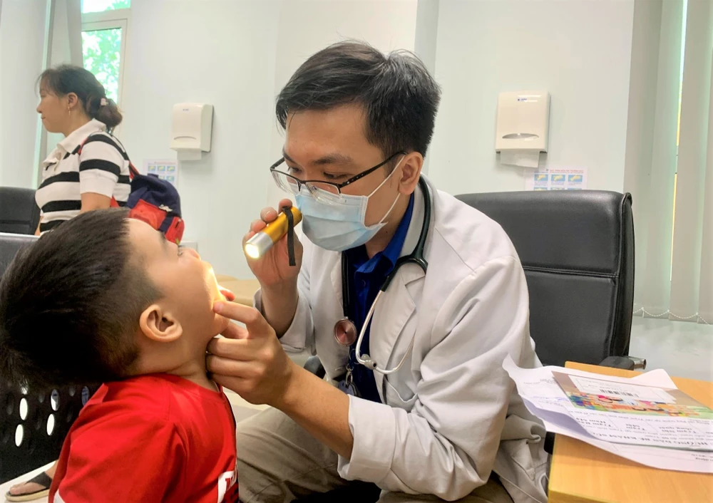 Bác sĩ khám tai mũi họng cho con chị Diễm. Ảnh: THẢO PHƯƠNG