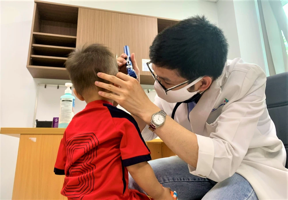 Bác sĩ khám tai cho bé trai. Ảnh: THẢO PHƯƠNG
