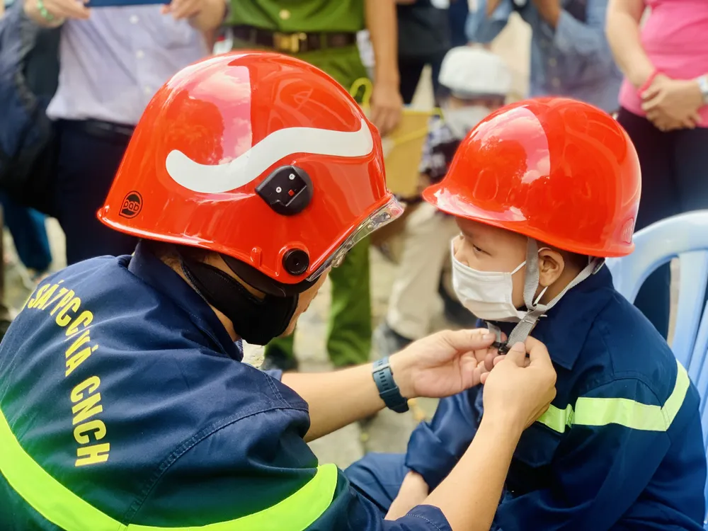 Quân được đội nón bảo hộ của lính cứu hỏa trước khi &quot;làm nhiệm vụ&quot;. Ảnh: THẢO PHƯƠNG