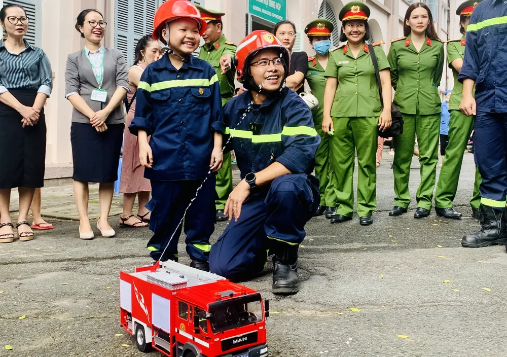 Nụ cười trên môi cậu bé khi được trải nghiệm công việc của lính cứu hỏa. Ảnh: THẢO PHƯƠNG