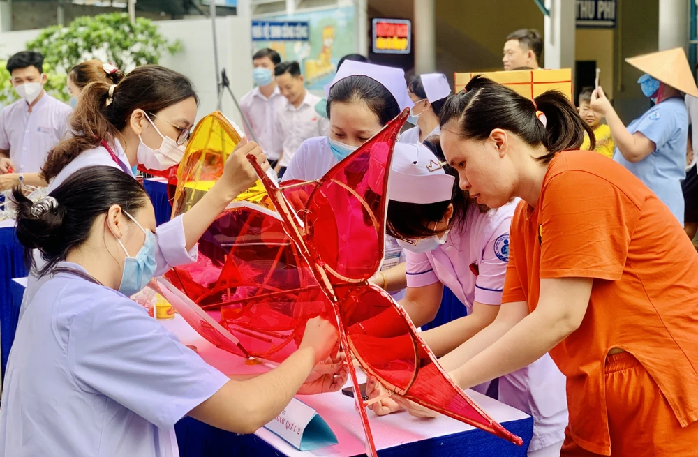 Chị Vũ Thị Hảo chăm chú cùng nhân viên y tế làm lồng đèn. Ảnh: THẢO PHƯƠNG trung-thu9.jpg