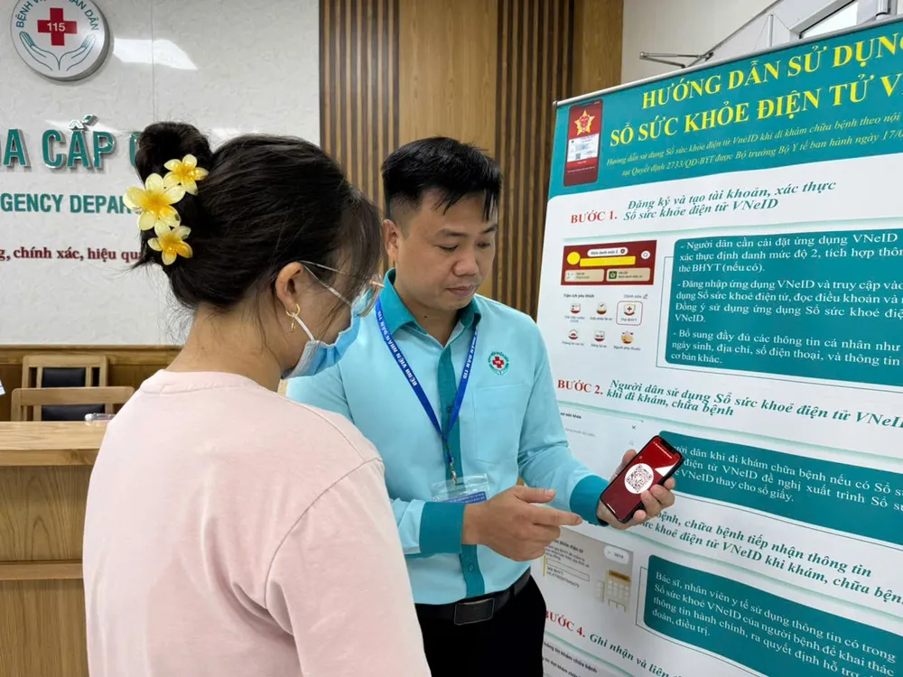 Nhân viên y tế Bệnh viện Nhân dân 115 hướng dẫn bệnh nhân, thân nhân đăng ký khám bệnh bằng sổ sức khỏe điện tử VNEID. Ảnh: BVCC so-suc-khoe-dien-tu2.jpg