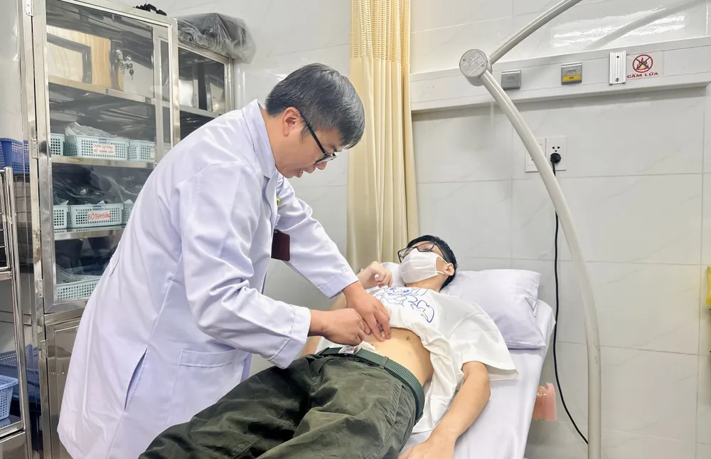 Bác sĩ Lê Tiến Dũng, khoa Ngoại Tiêu hóa Bệnh viện Thống Nhất, thăm khám cho bệnh nhân thủng dạ dày. Ảnh: THẢO PHƯƠNG bệnh nhân thủng dạ dày