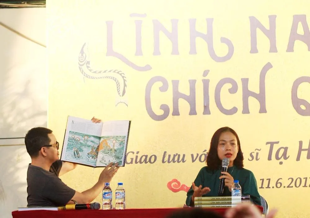 Họa sĩ Tạ Huy Long (trái) giới thiệu về các hình minh họa của mình trong sách.