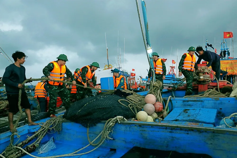 Lực lượng vũ trang huyện Hải Hậu giúp ngư dân chằng buộc tàu, thuyền tại cảng cá Ninh Cơ. bão số 3