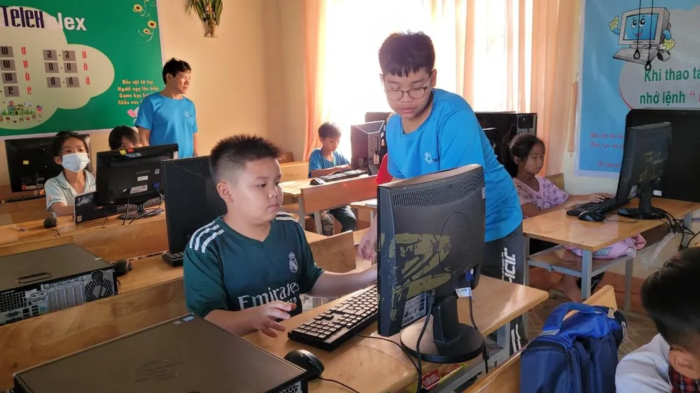 Hai cha con anh Sơn hướng dẫn các em học dinh tiểu học thực hành tin học. Ảnh: Kha Nhiên