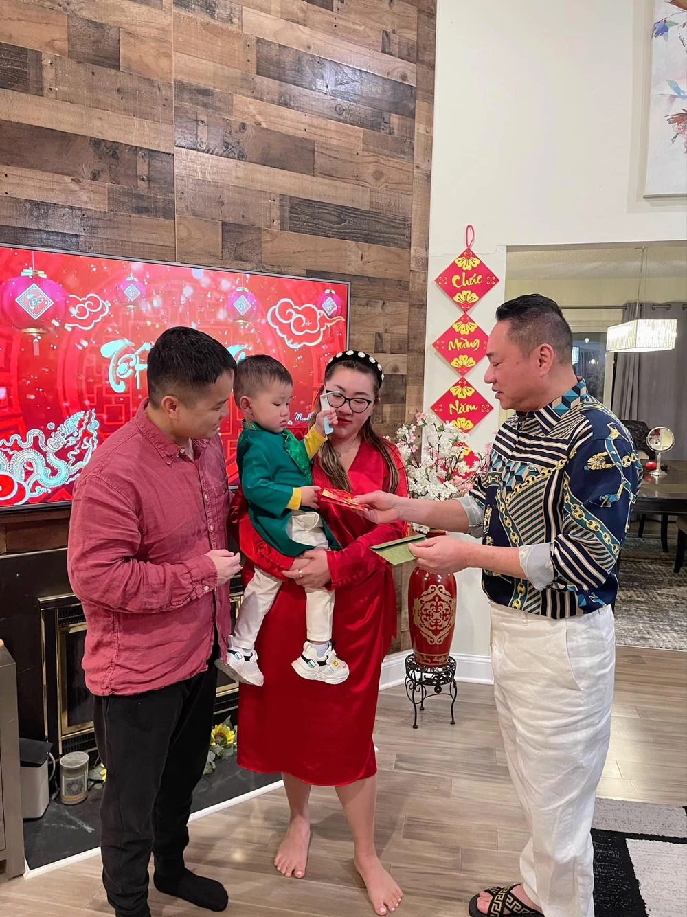 Ông Dân lì xì cho con cháu, đồng thời nhận lại các lời chúc bình an, may mắn. chu dan lixi.jpeg