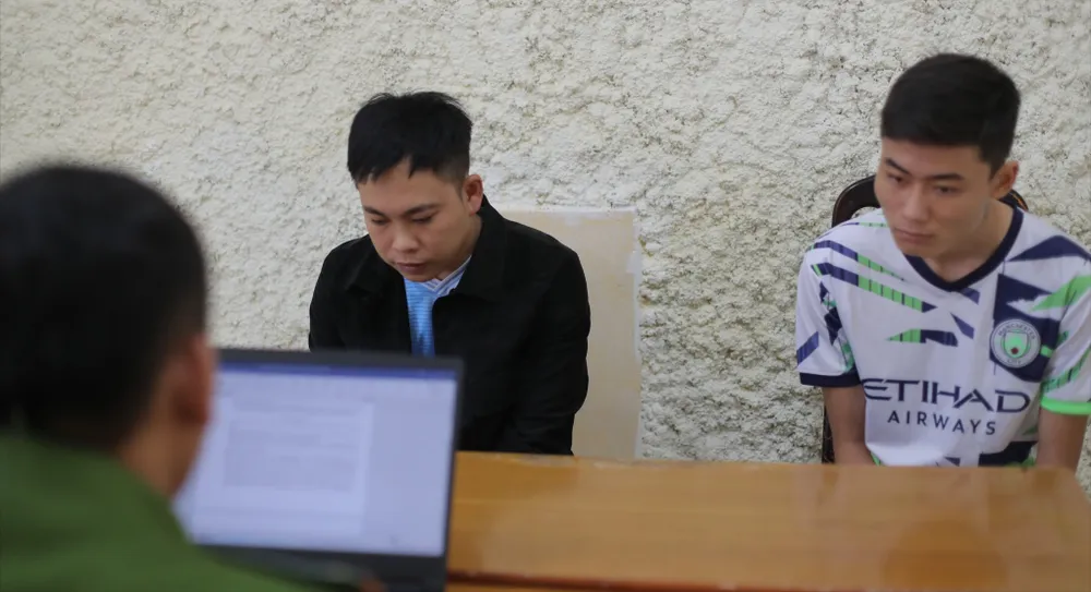 Đạt (áo đen) và Tuấn bị công an bắt giữ dl.jpg