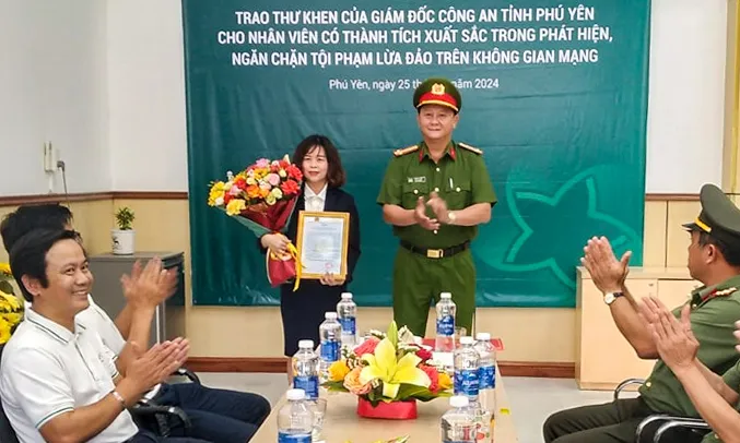 Đại diện Công an tỉnh Phú Yên trao thư khen cho nữ nhân viên ngân hàng. Ảnh: MT lừa.jpg