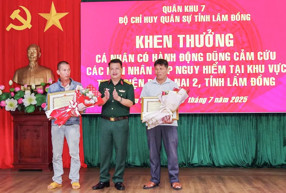 Đại tá Đinh Hồng Tiếng, Chỉ huy trưởng Bộ Chỉ huy Quân sự tỉnh Lâm Đồng, trao bằng khen, hoa cho hai cá nhân đã cứu ba người, hôm 16-7. Ảnh: TRÙNG DƯƠNG c8.jpg