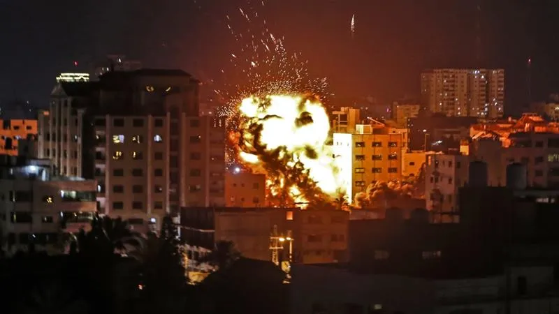 An explosion is pictured among buildings during an Israeli air raid on Gaza City on May 4 [Mahmud Hams/AFP]