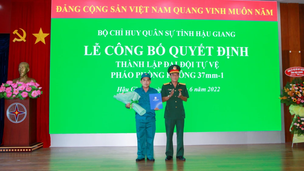 Đại tá Đặng Hoàng Khởi (bìa phải), Phó Chỉ huy trưởng Bộ Chỉ huy Quân sự tỉnh trao Quyết định thành lập Đại đội tự vệ pháo phòng không 37mm-1 Công ty Điện lực Hậu Giang. Ảnh: VĂN NGUYỄN