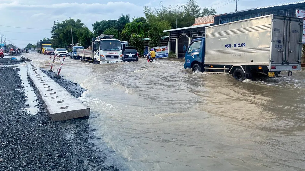 Tình trạng ngập nhiều đoạn trên Quốc lộ làm lưu thông của người và phương tiện rất khó khăn. Ảnh: PHẠM TRINH