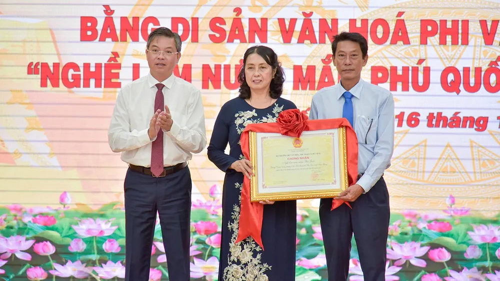 Ông Nguyễn Lưu Trung (bìa trái), Phó Chủ tịch UBND tỉnh Kiên Giang trao bằng công nhận di sản văn hóa phi vật thể cho UBND TP Phú Quốc và Hội nước mắm. Ảnh; TUẤN THY