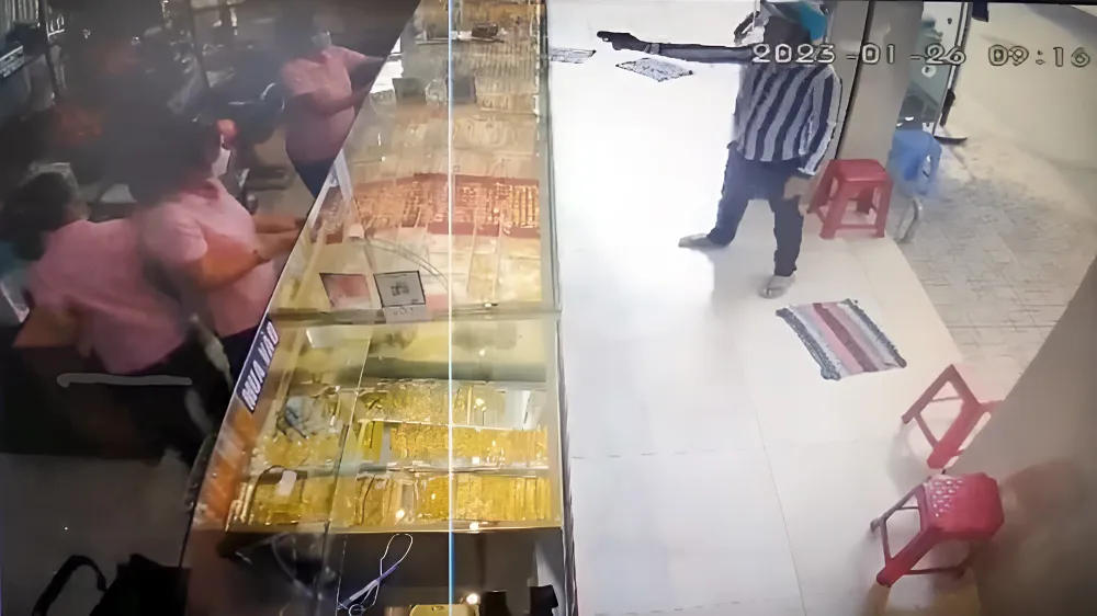 Bị can Tăng Minh Phúc (áo sọc) lấy ra một vật giống súng đe dọa nhân viên tiệm vàng TT ở TP Sóc Trăng nhằm cướp tài sản. Ảnh: DIỄM HẰNG