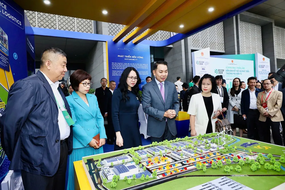 Bà Lê Hoàng Oanh, Cục trưởng Cục Thương mại điện tử và Kinh tế số (áo dài) cùng các khách mời tham quan các gian hàng triển lãm về logistics, thương mại điện tử. Ảnh: AH thương mại điện tử....jpg