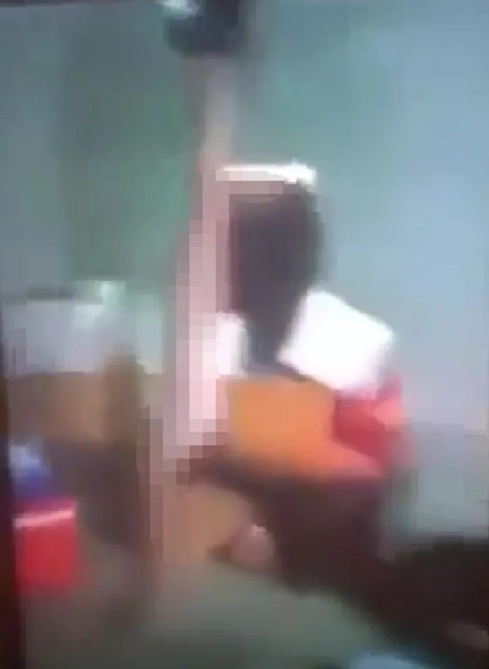 Bé gái bị lột hết quần áo, treo hai tay lên trần nhà và hành hạ. Ảnh: Cắt từ video clip.