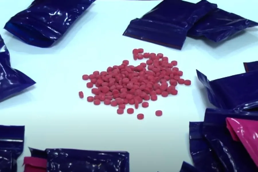 Mở tang vật thu từ Lê Văn Bốn ra có nhiều gói ni lông chứa hồng phiến với tổng cộng 3.000 viên hồng phiến. Ảnh cắt từ video clip.