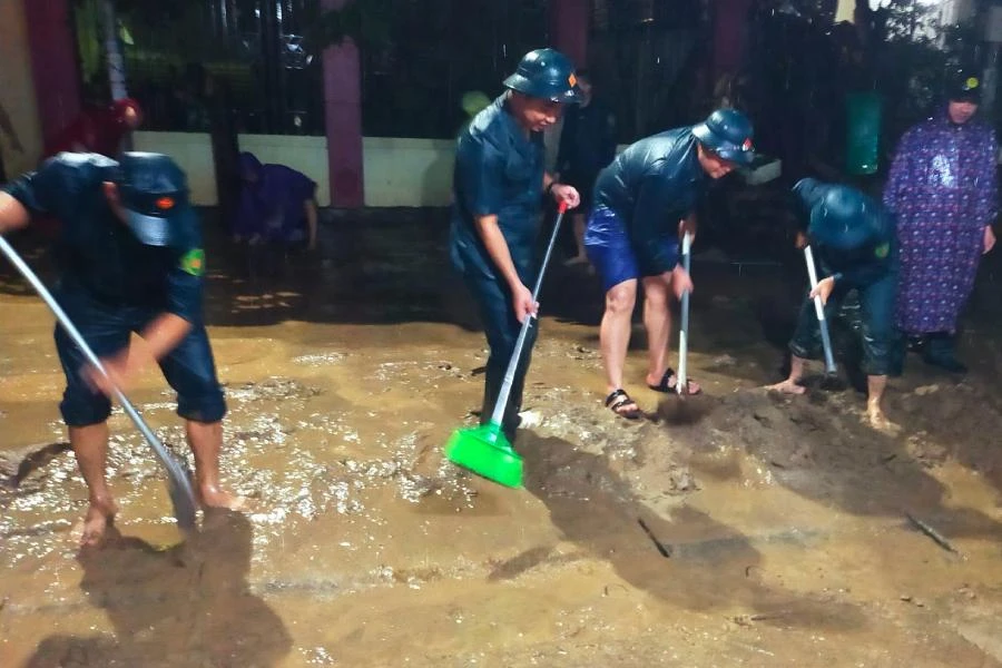 Lực lượng chức năng giúp người dân dọn bùn sau lũ. Ảnh: ĐẠI NGÀN.