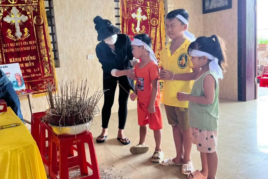 Ba đứa nhỏ trước di ảnh của bố, mẹ.