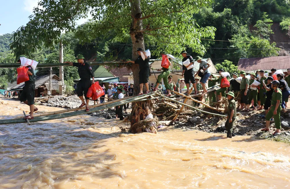 Các chiến sĩ đi cầu khỉ bắc qua suối vào giúp đỡ người dân xã Tà Cạ- bị thiệt hại nặng trong cơn lũ quét sáng 2-10.