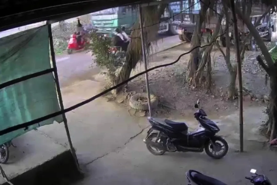 Camera nhà dân bên đường ghi được khung cảnh tài xế Quân điều khiển xe tải (màu xanh) tránh ô tô tải và xe máy ngược chiều, tông vào xe máy (màu đỏ) của người mẹ chở 3 con nhỏ.