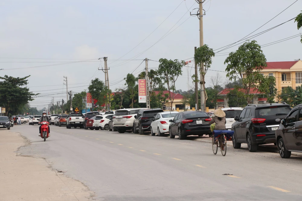 Xe ô tô đậu kín bên đường dẫn đến hội trường trụ sở UBND xã Nghi Phong- nơi đang diễn ra đấu giá 114 lô đất ở nông thôn. Ảnh: ĐẮC LAM