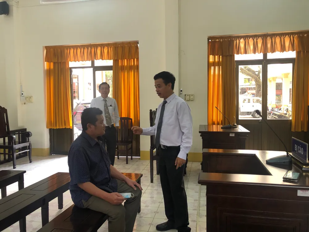 Ông Xoa (ngồi) trao đổi với luật sư trước khi toà tuyên trả hồ sơ. Ảnh: YC