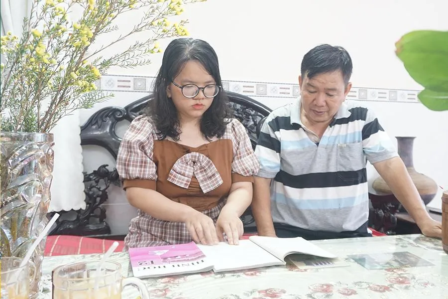 Thầy Mai Thành Nam đang trao đổi bài với con gái Mai Đỗ Thúy Uyển. Ảnh: NQ